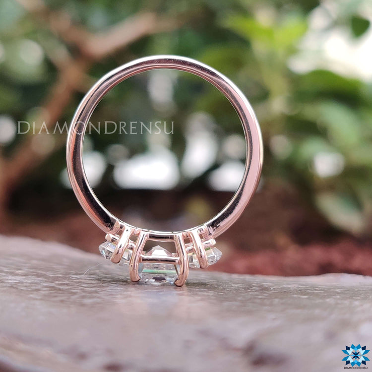 Prong set moissanite ring with emerald accents.
