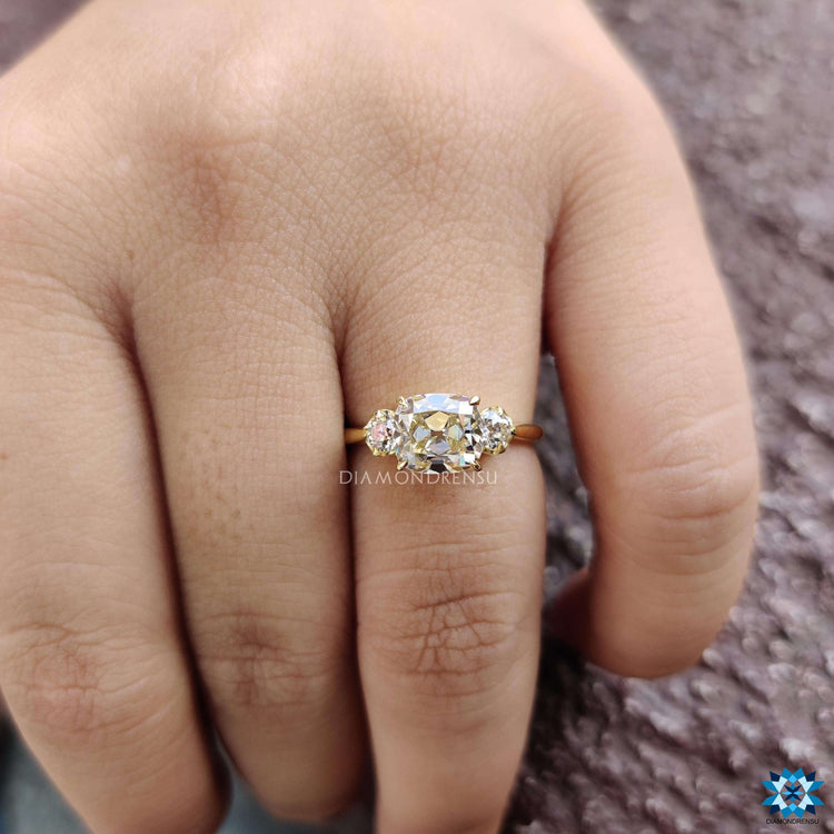Handmade engagement ring featuring a cushion cut center stone in soft yellow hue.
