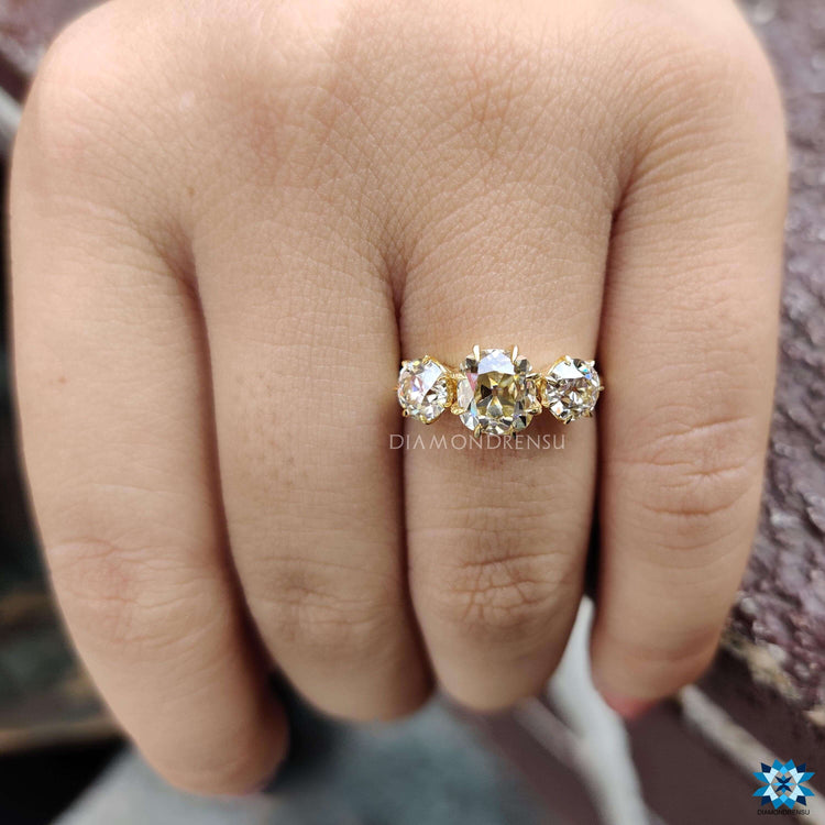 Yellow gold ring featuring cushion and round old cut stones.
