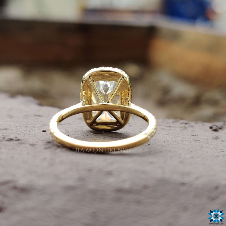 Yellow gold halo ring with cushion moissanite center.
