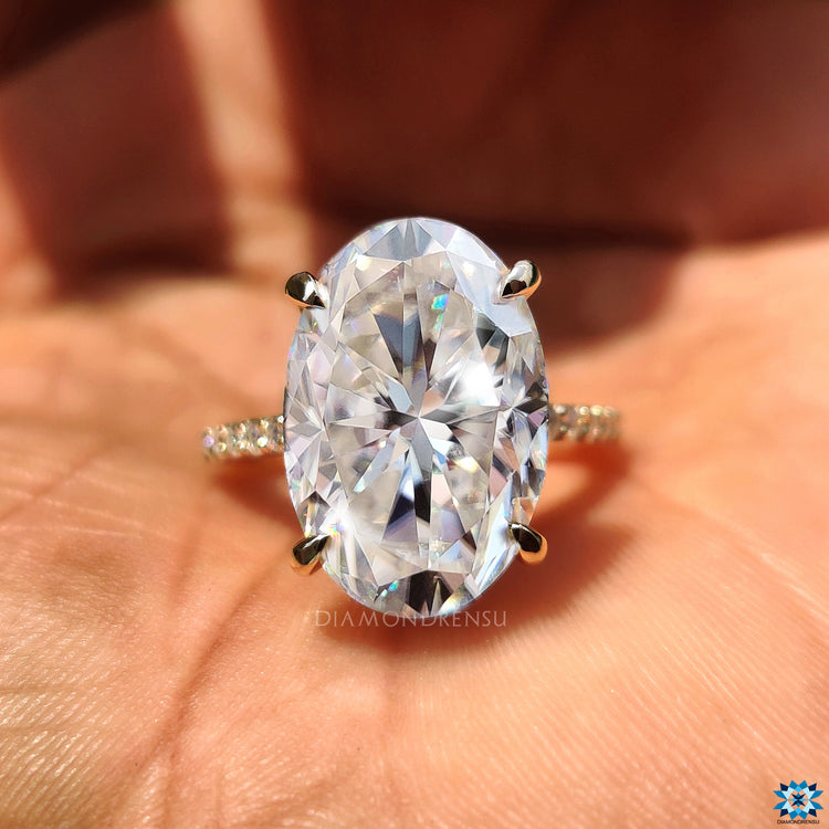 Hidden halo oval moissanite ring with elegant round cut pave band in yellow gold.
