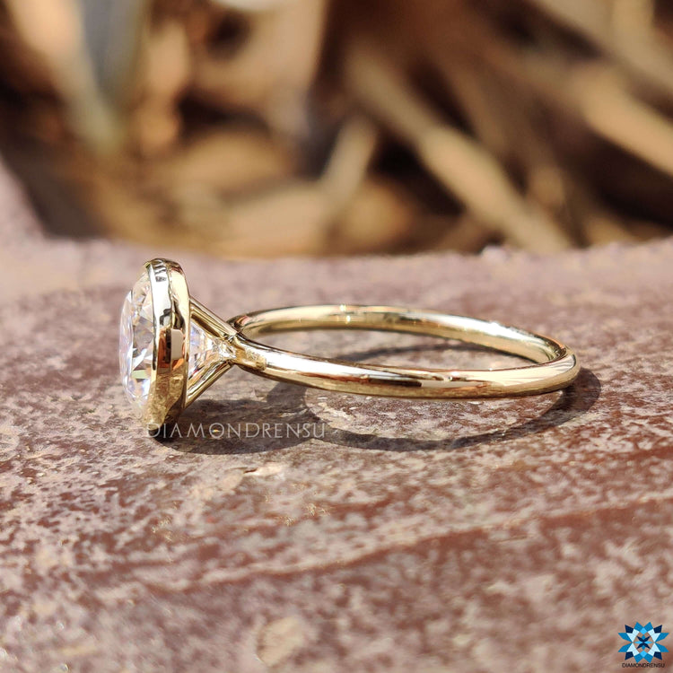 Minimalist moissanite ring with bezel setting in yellow gold.

