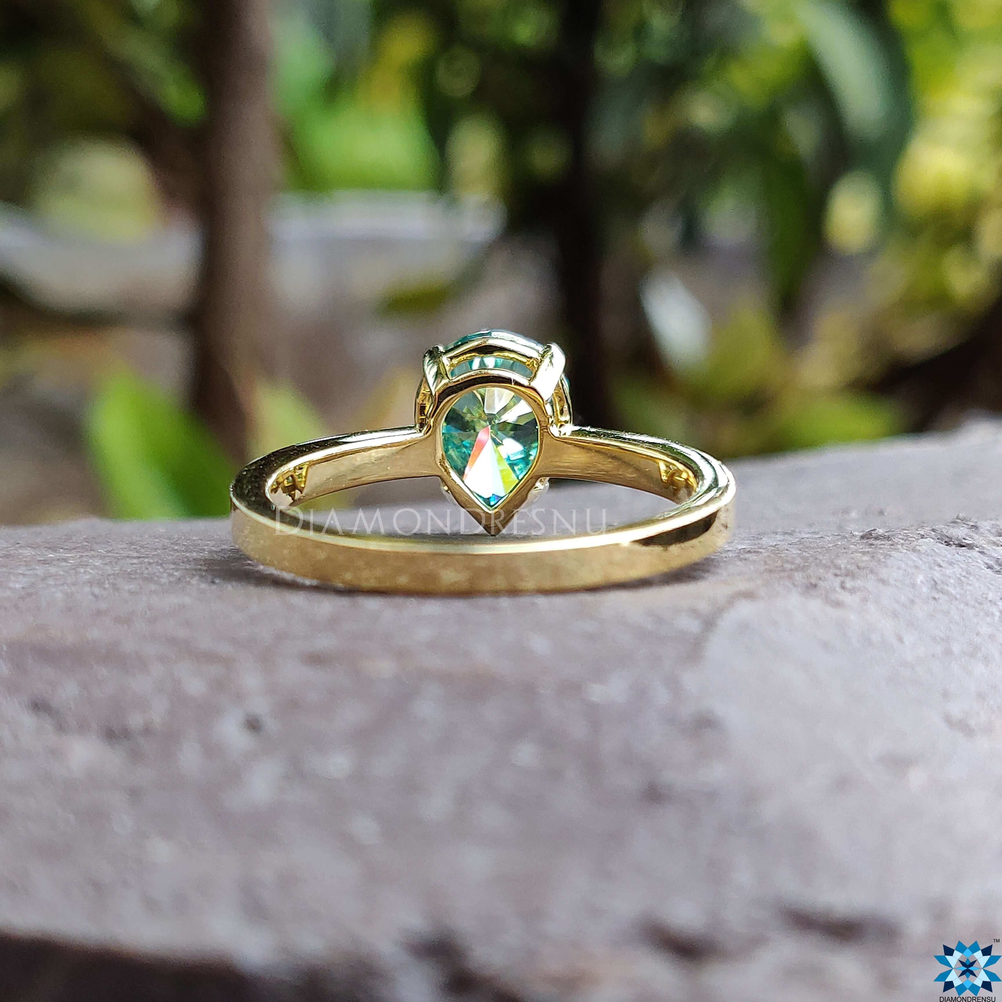 Handmade ring featuring a radiant green moissanite stone in a pear shape.