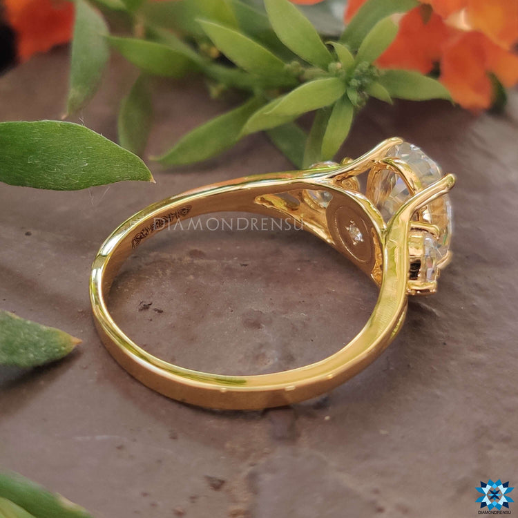 Prong setting gold ring with oval and round moissanite stones.
