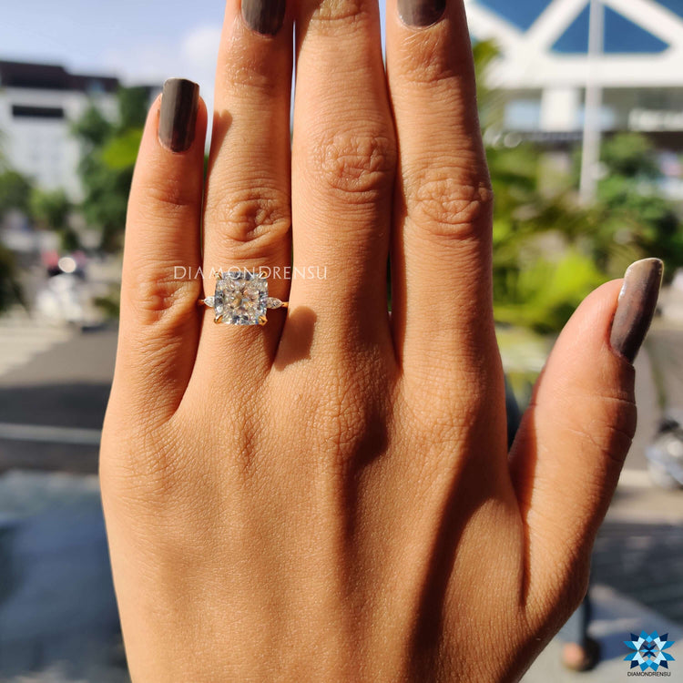 Moissanite engagement ring in yellow gold with a cushion centre and pear sides.
