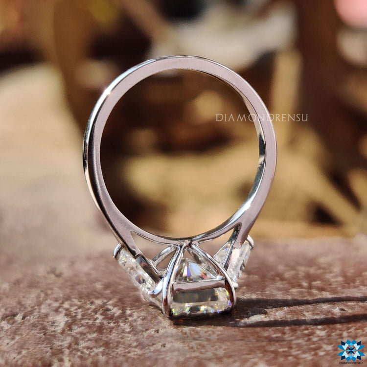 Custom radiant engagement ring with claw prong and side trillions.
