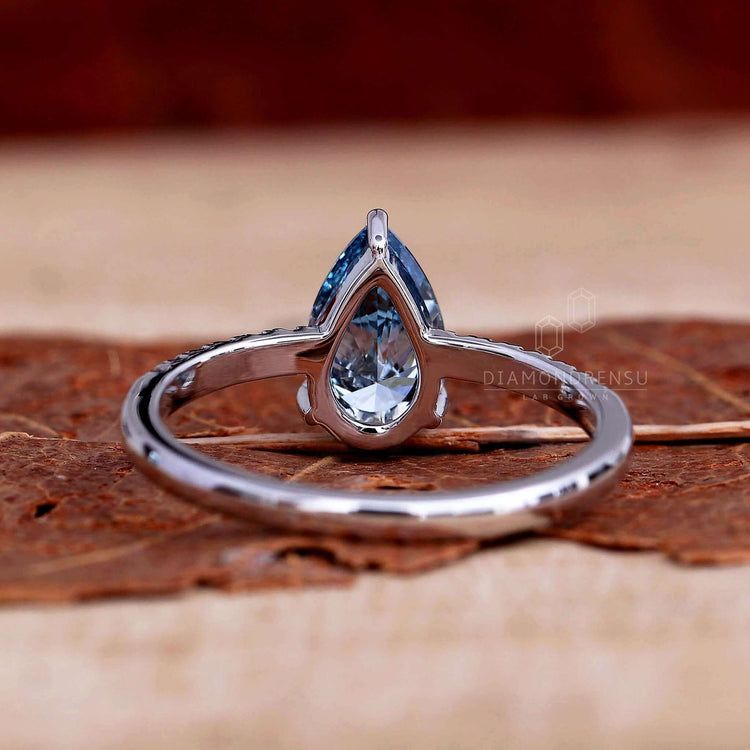 Pear ring showcasing a blue pear diamond with a stunning pave ring setting.
