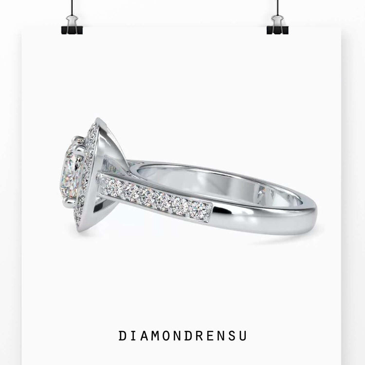 Round prong setting holding cushion cut diamond in halo design.
