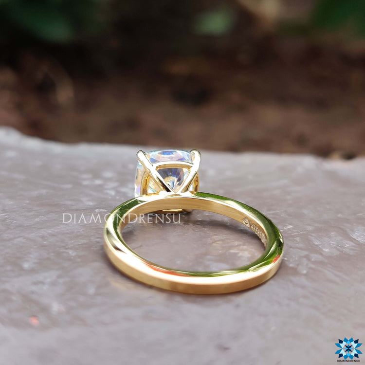 4 prong claw setting securing a cushion cut moissanite in yellow gold.
