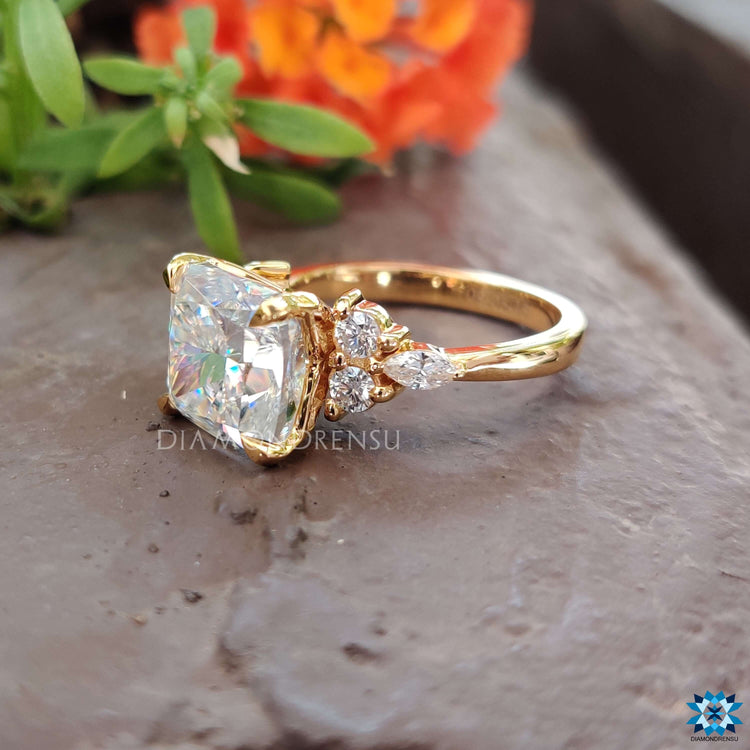 Moissanite engagement ring in yellow gold with 4 claw prong and side stone detailing.
