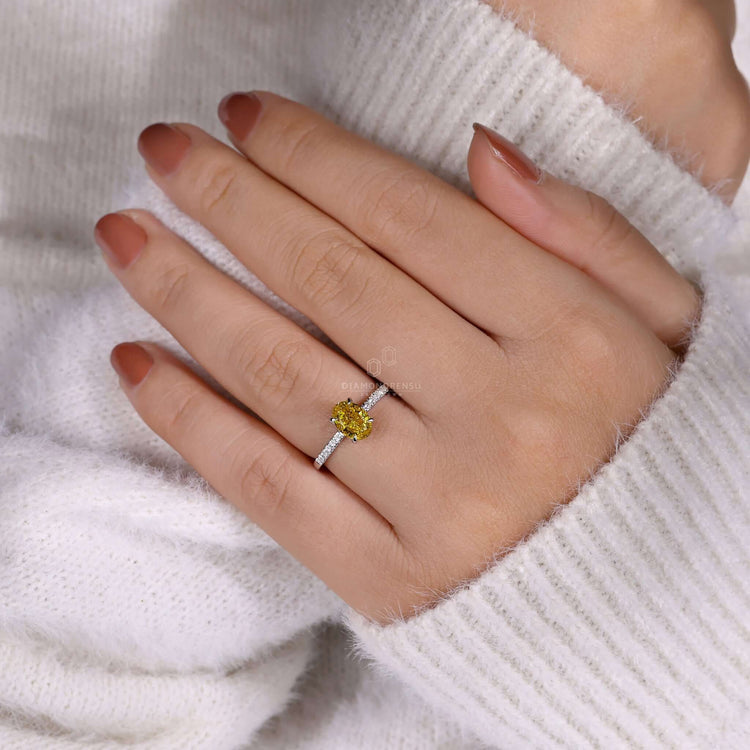 Oval yellow diamond engagement ring with a hidden halo and claw prong setting for a luxurious touch.

