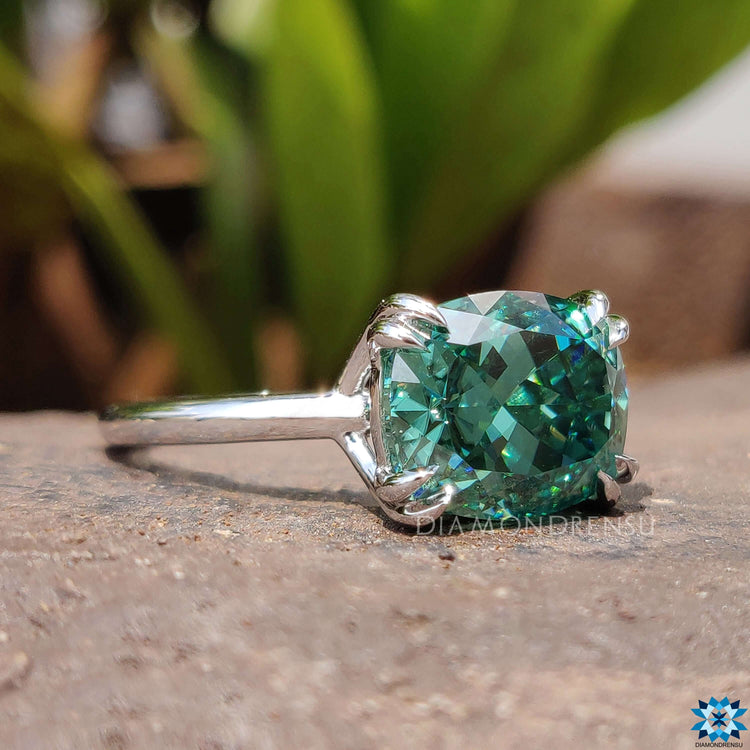 White gold ring with green moissanite center.
