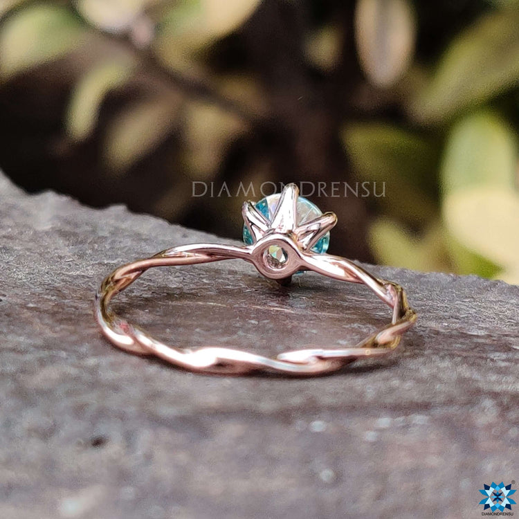 Twisted band rose gold ring with round moissanite.

