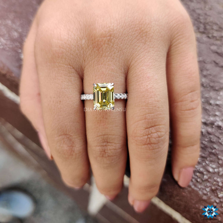 Radiant yellow emerald moissanite ring with round pave accents.
