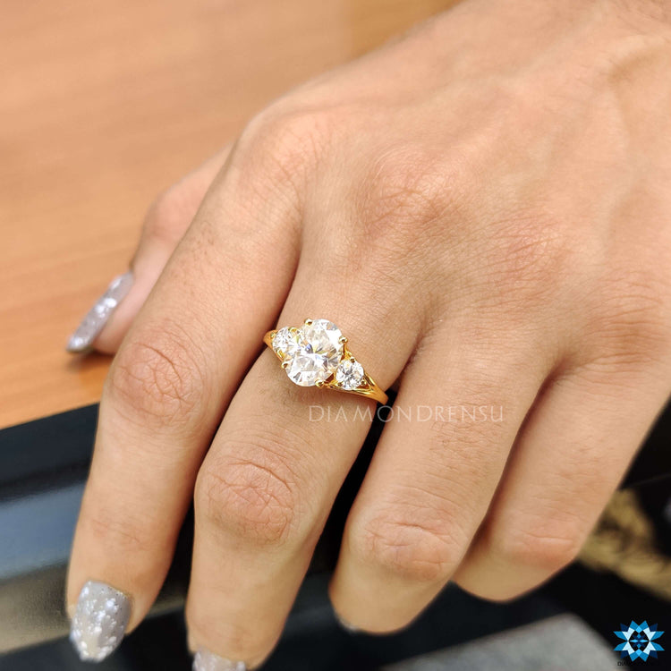 Yellow gold custom ring featuring three moissanite stones.
