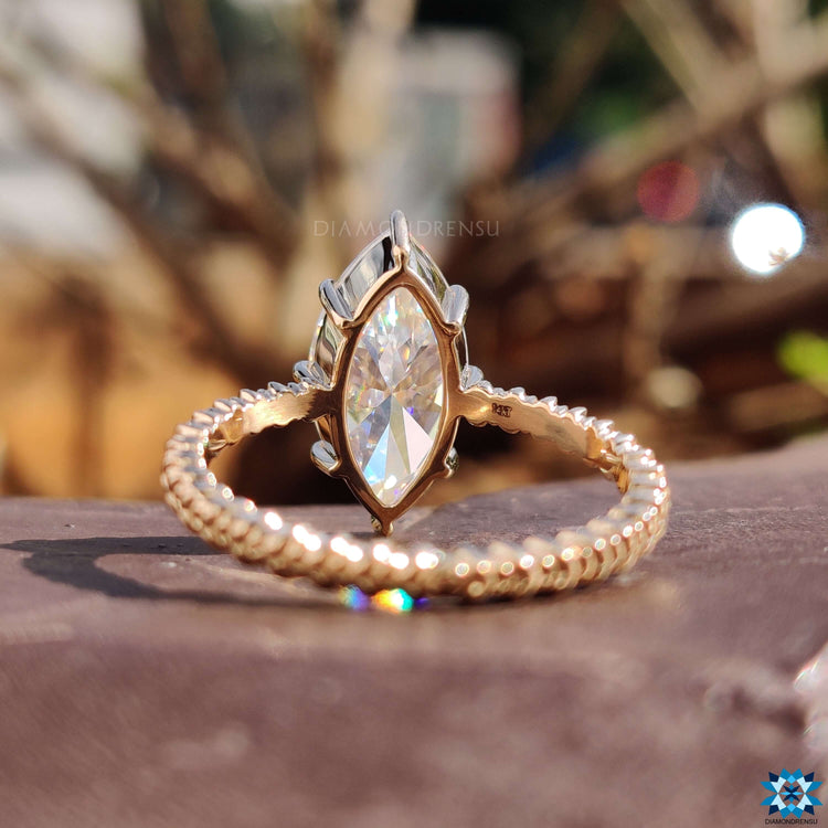 Twisted band ring with marquise cut moissanite.
