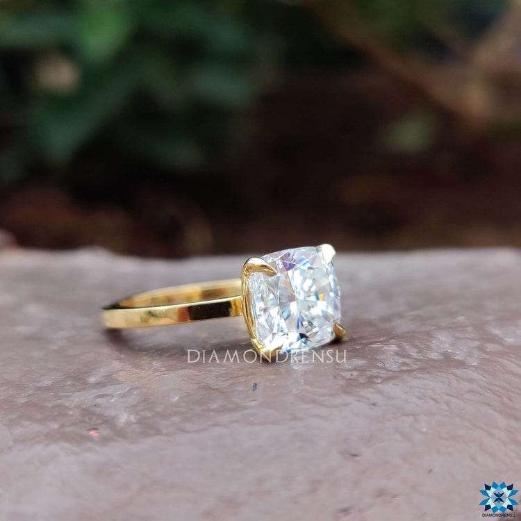 Yellow gold moissanite ring with a cushion cut solitaire design.
