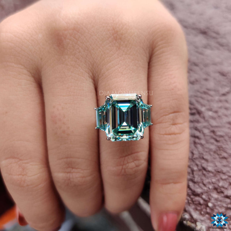 Three stone engagement ring with emerald cut center stone.
