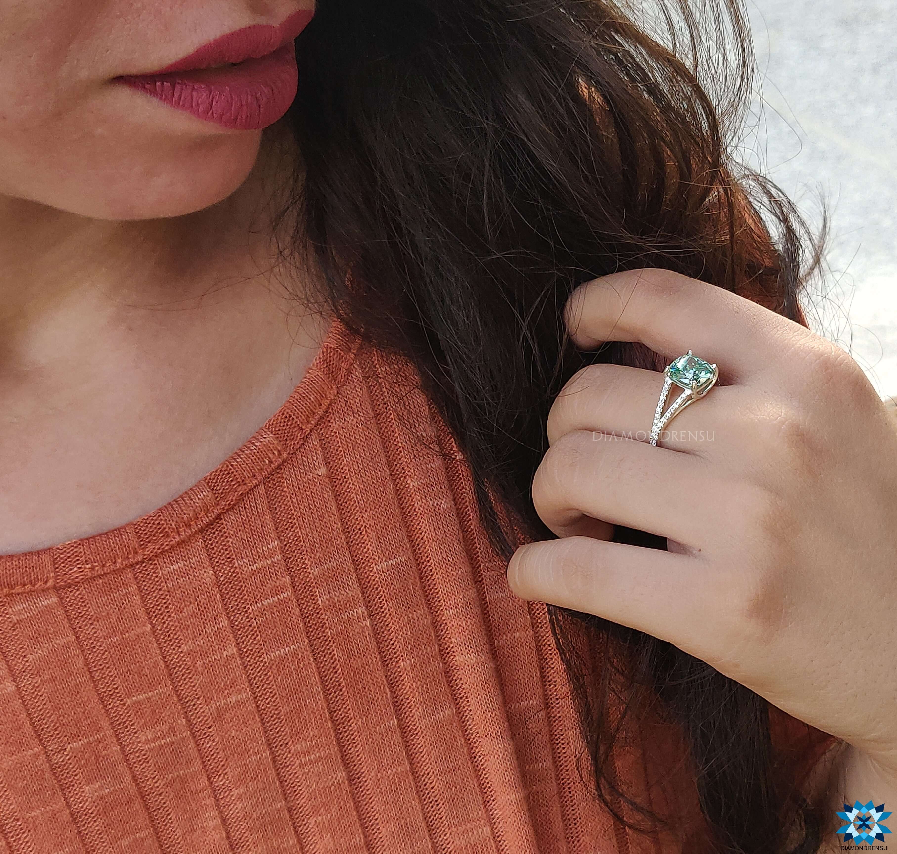 White gold engagement ring featuring a cushion cut moissanite centre and split shank.