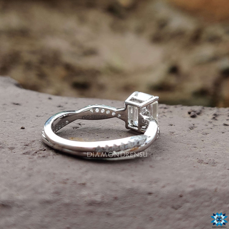Twisted pave band ring with emerald cut moissanite center.
