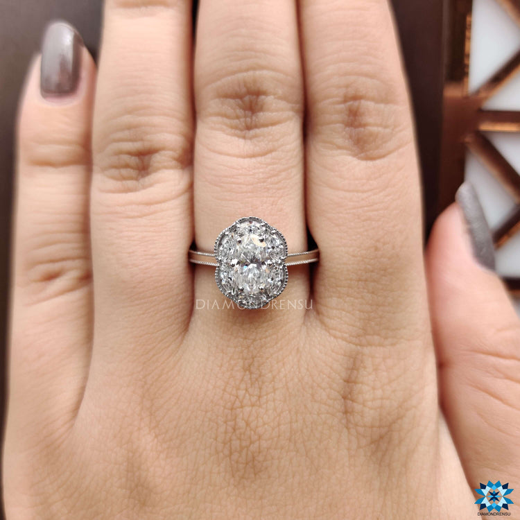 White gold ring with oval moissanite and marquise cluster halo.
