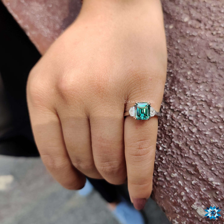 Moissanite engagement ring with green Asscher cut stone.
