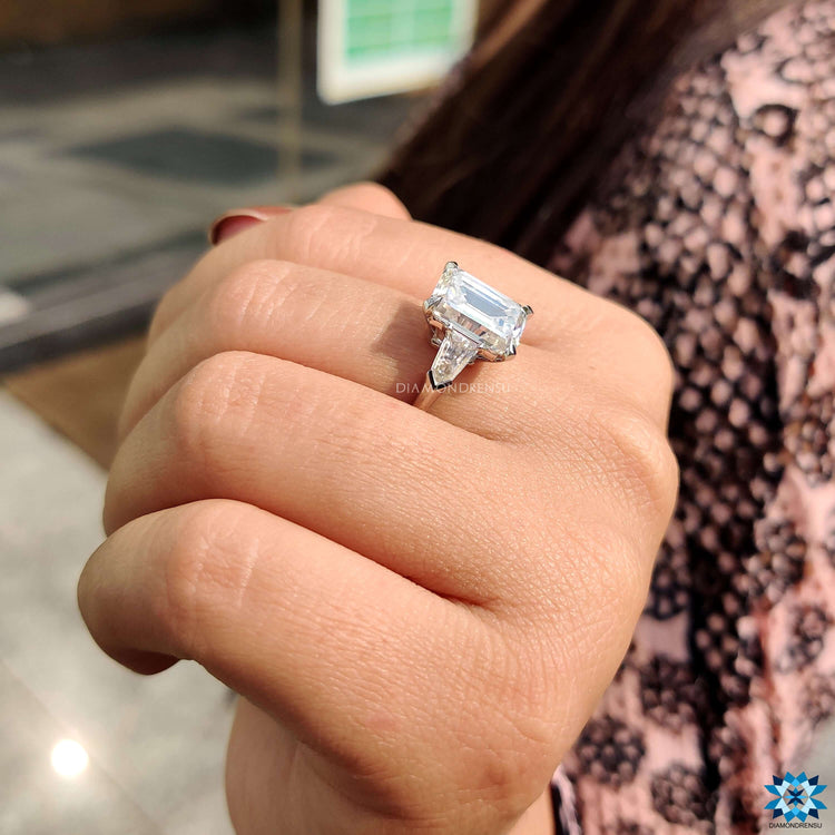 Custom three stone engagement ring in white gold with emerald cut moissanite.
