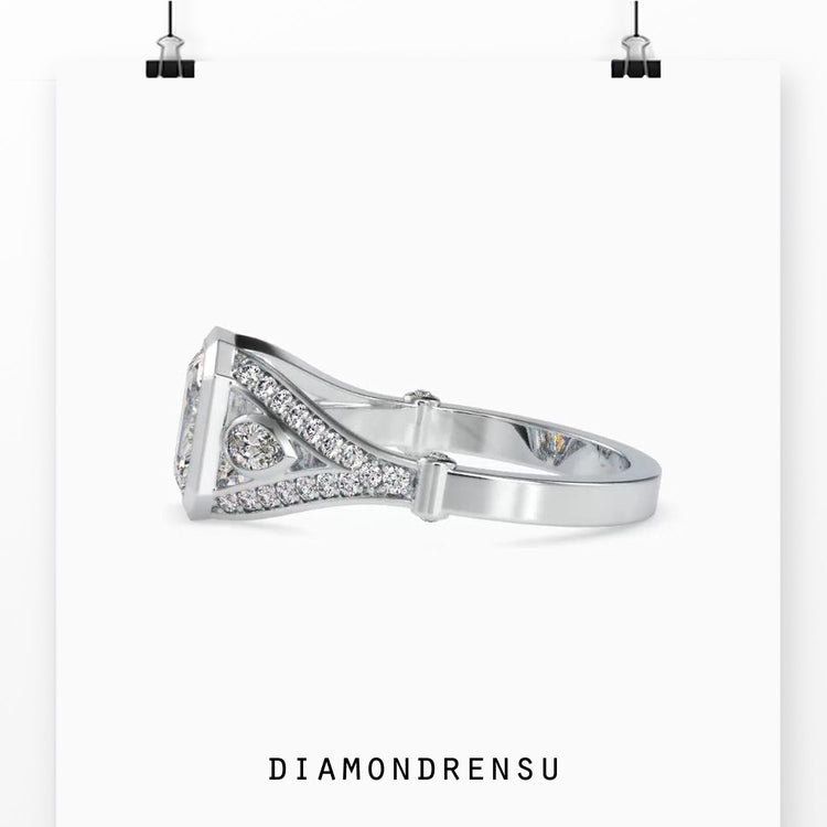 Split shank engagement ring featuring emerald and pear diamonds.

