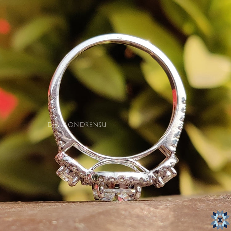 Round cut moissanite ring with halo and side stones.

