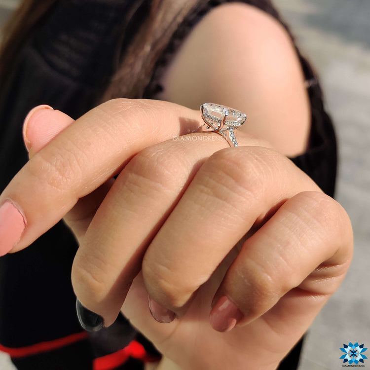 Engagement ring with emerald cut moissanite and hidden halo design.

