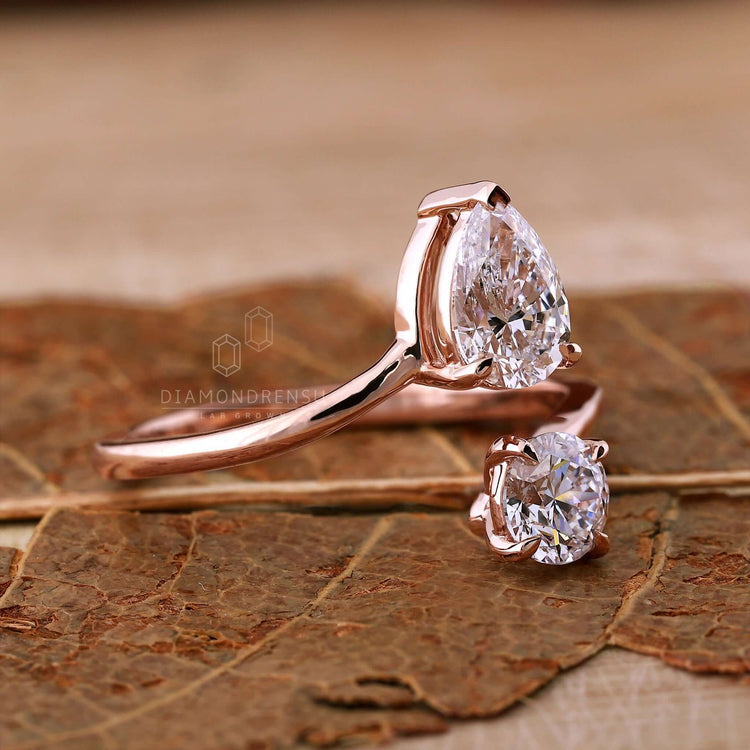 Open gap bypass setting ring with round cut diamond and pear cut diamond for modern sophistication.
