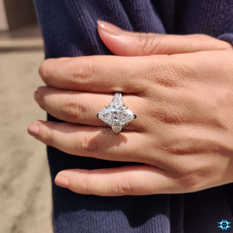 Double claw prong moissanite ring with marquise center and tapered sides.
