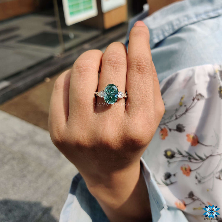 Three stone moissanite ring featuring an oval cut center and pear side stones.
