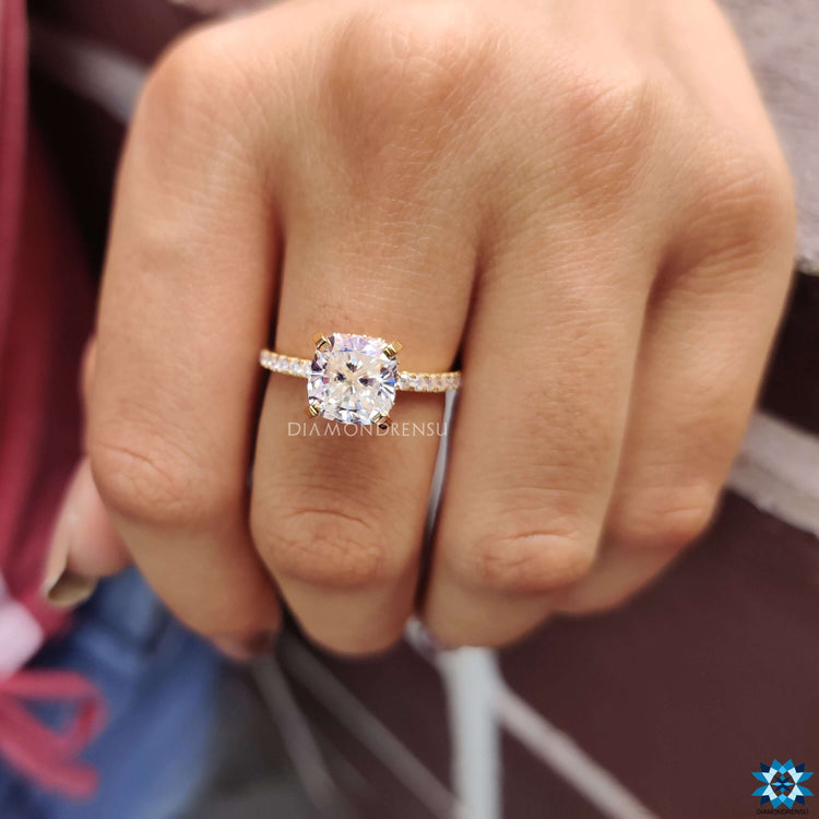 Cushion moissanite ring in yellow gold with round cut pave accents.
