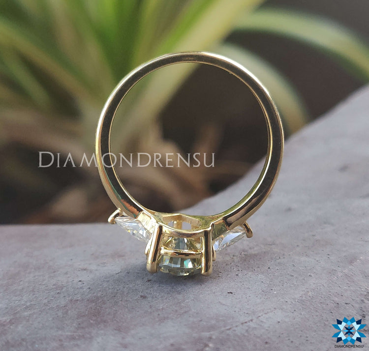 Prong setting ring with triangle side stones and pear shaped diamond.