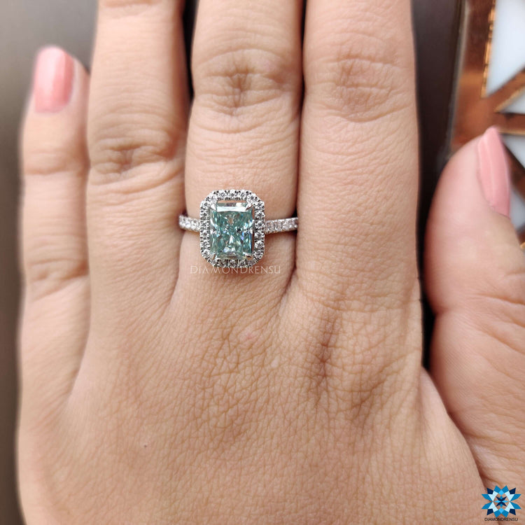 White gold engagement ring with radiant moissanite and round side accents.
