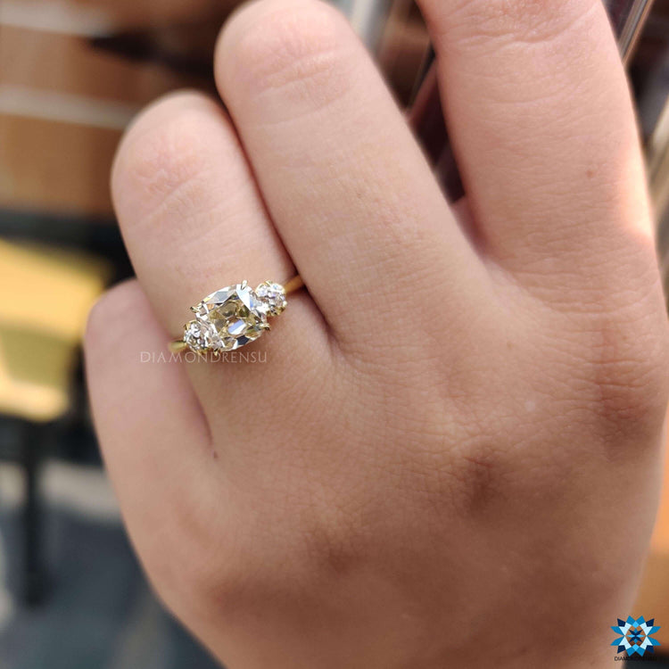 Engagement ring crafted with a light yellow cushion cut moissanite and two matching side stones.
