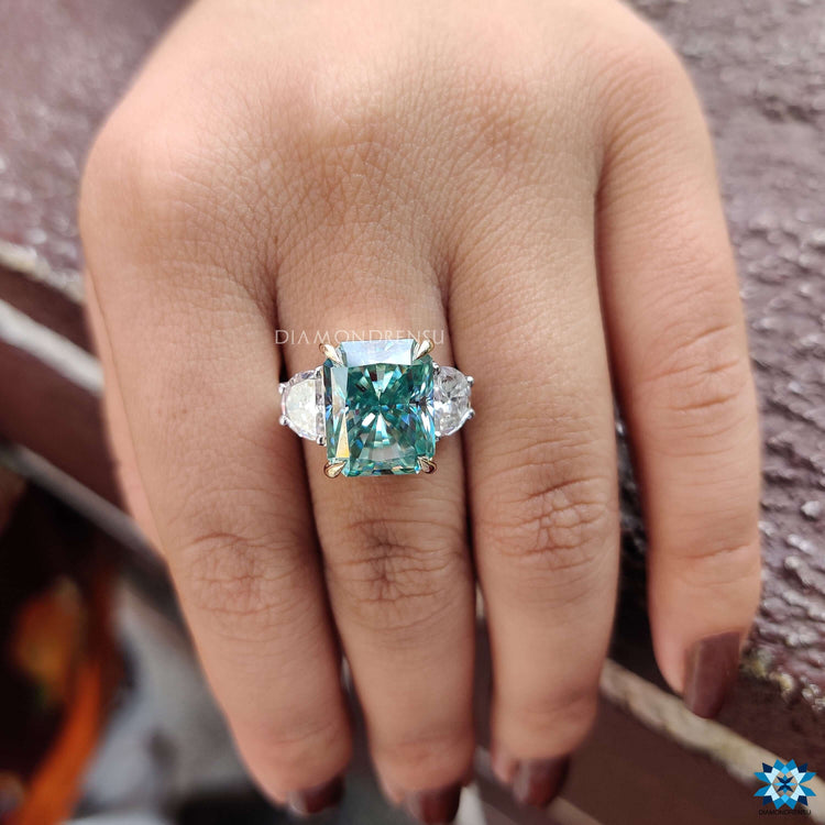 Three stone ring with radiant cut cyan blue moissanite.
