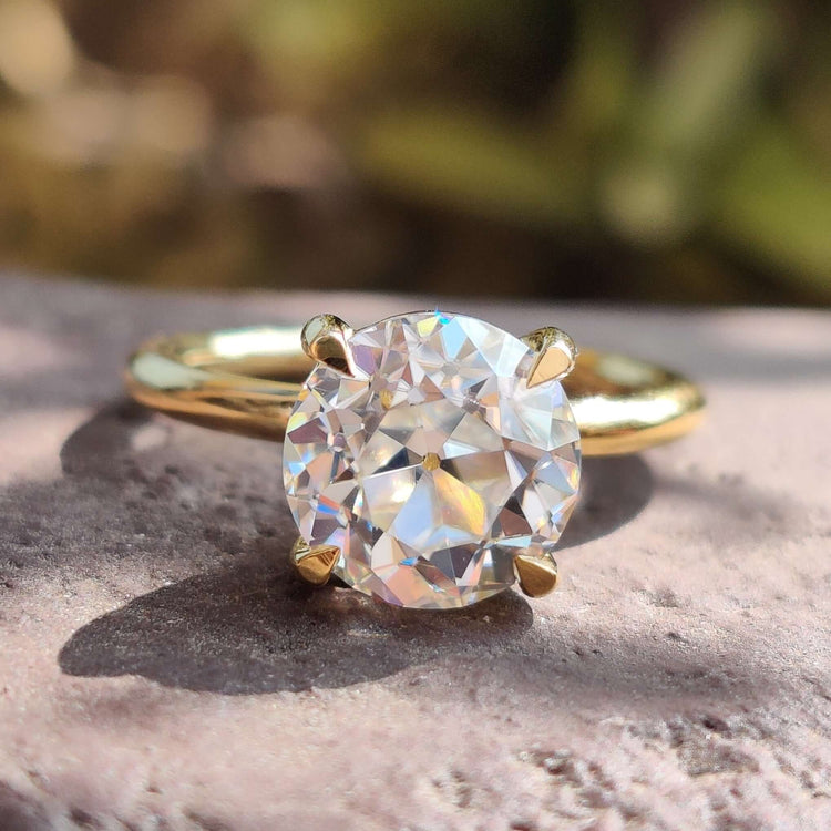 Round solitaire moissanite engagement ring in yellow gold.
