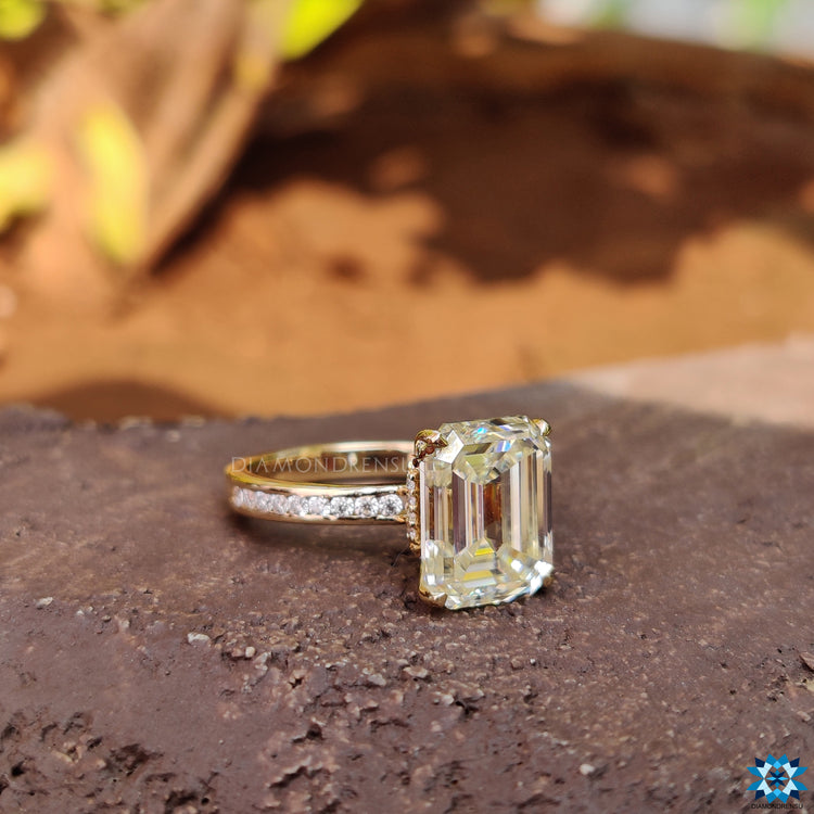 Yellow gold ring featuring hidden halo and emerald cut moissanite stone.
