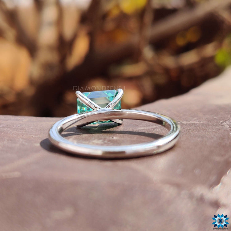 Solitaire engagement ring with green moissanite center.
