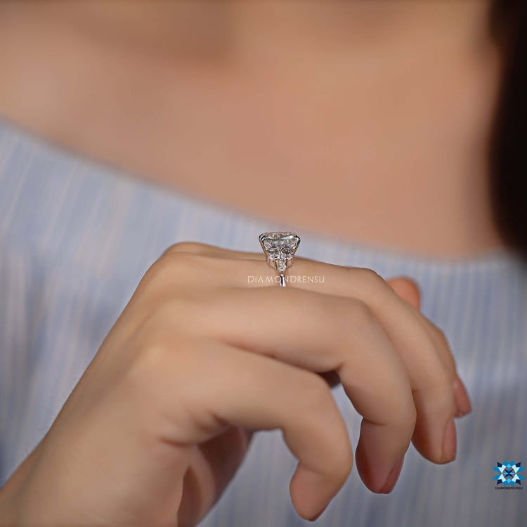 Cushion moissanite ring with marquise side stones in a white gold band.

