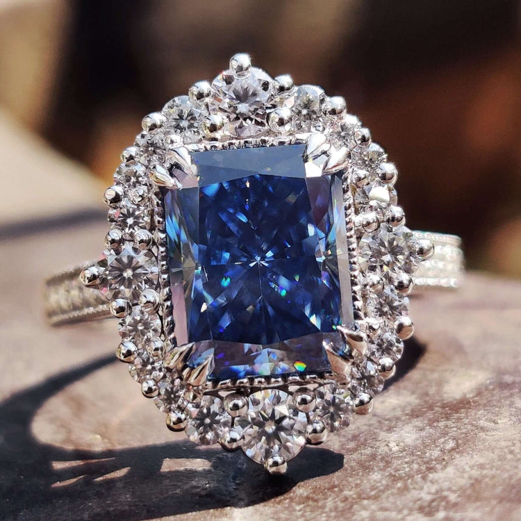 Radiant cut blue moissanite ring with milgrain detailing.
