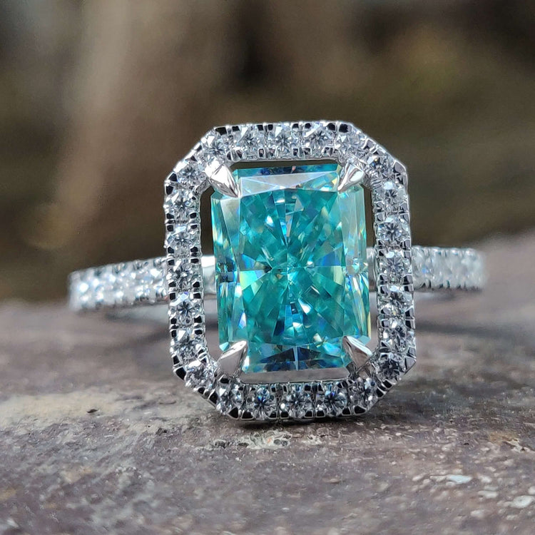 Radiant cut blue moissanite engagement ring with halo setting.
