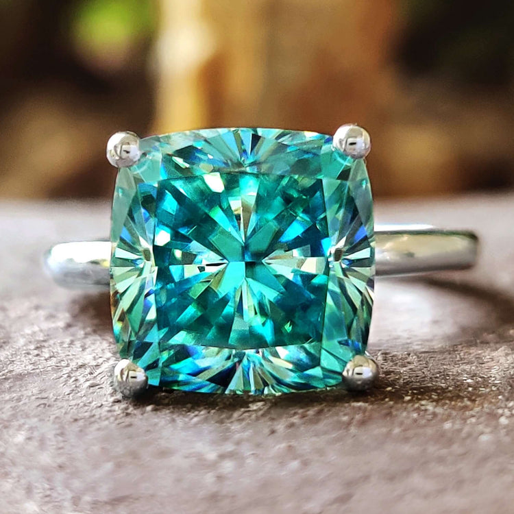Cushion cut ring with cyan blue moissanite.
