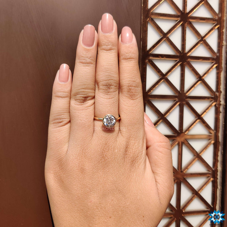 Solitaire ring with bezel mount holding a round moissanite.
