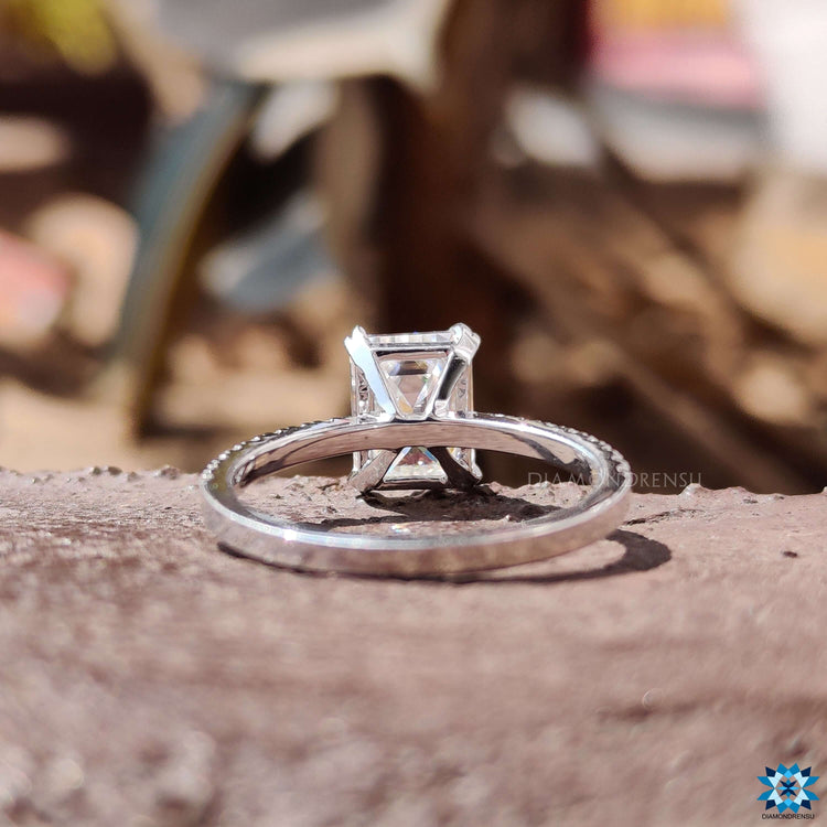 Custom white gold ring featuring emerald cut moissanite and pave details.
