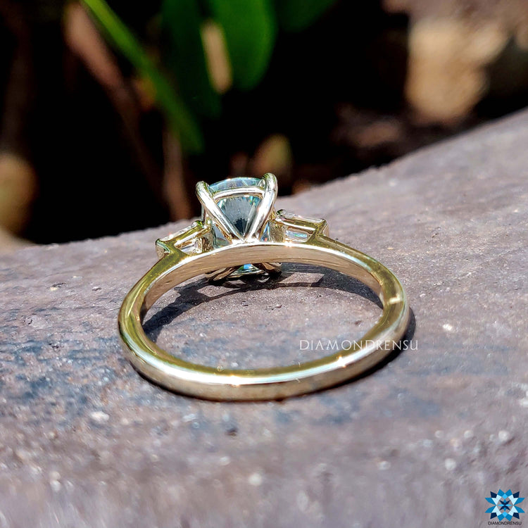Custom engagement ring with tapered baguette and blue center stone.

