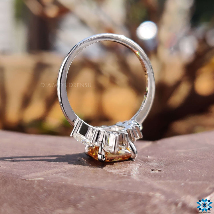 Cushion moissanite ring with pear and round cut side stones in prong setting.
