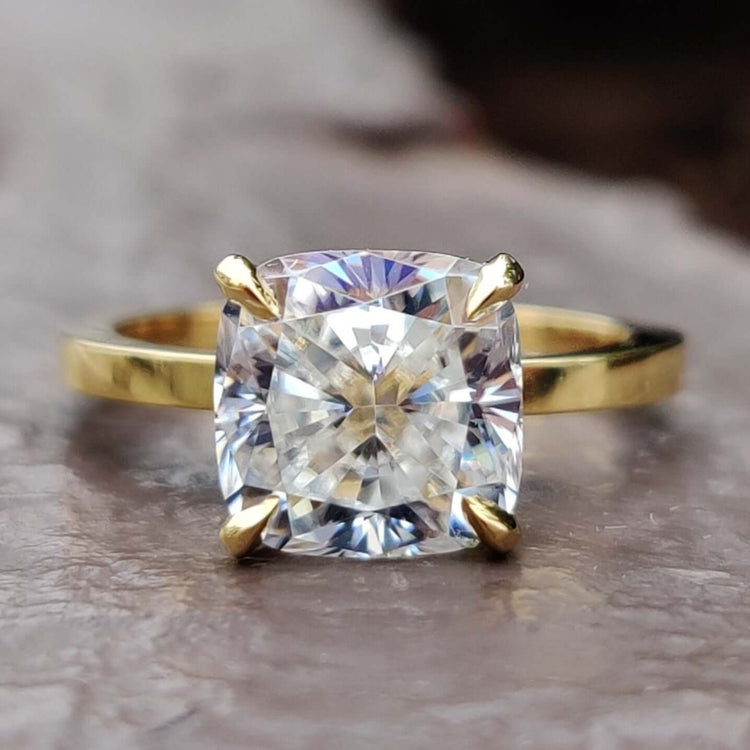 Cushion cut solitaire ring with a yellow gold band and moissanite centre.
